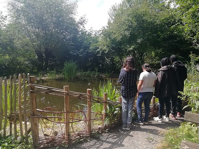 Eine Gruppe von Jugendlichen steht an einem See in einem Park.
