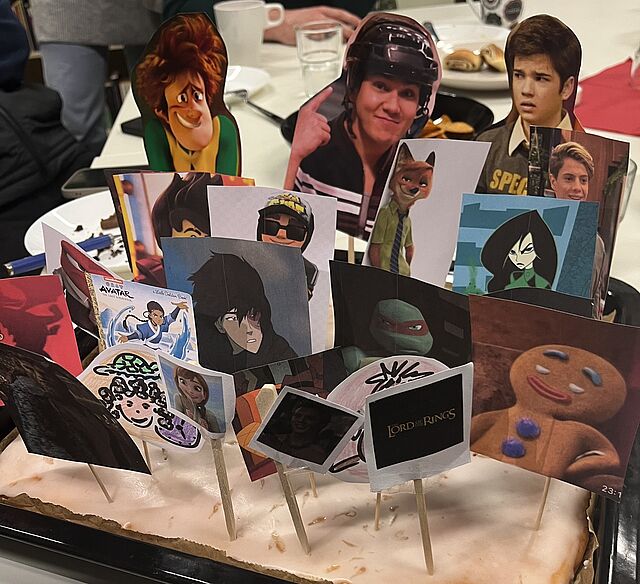 Auf einem Blechkuchen stecken kleine Bilder von Comic- oder Filmfiguren.
