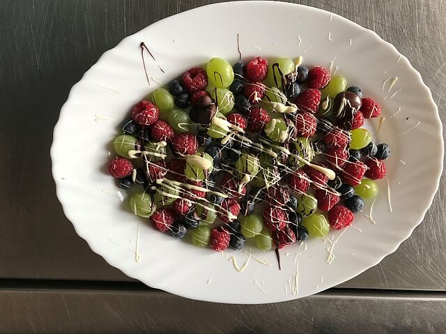 auf einem Teller liegen Beeren und Obststücke mit Schokolade überzogen