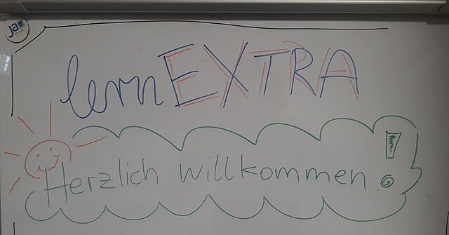 Herzlich willkommen steht auf einem Whiteboard geschrieben.