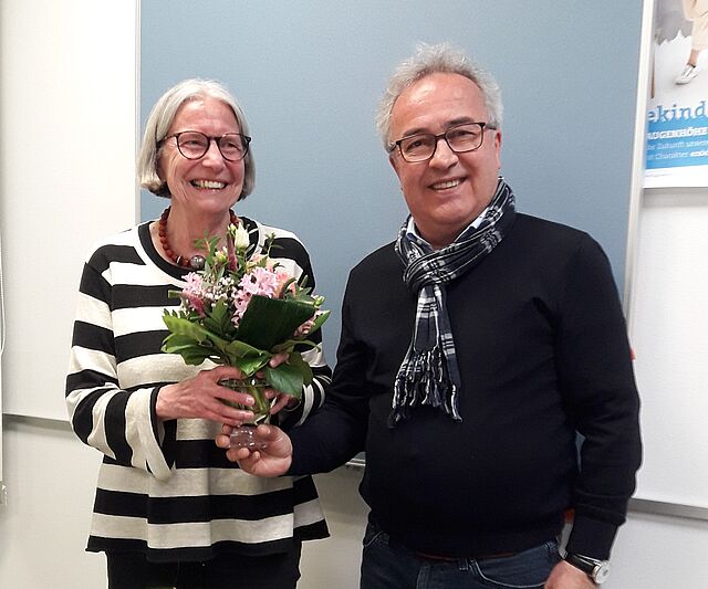 Frau mit Blumenstrauss und Mann lachen in die Kamera.