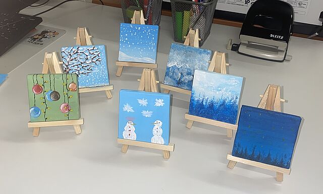 Weihnachliche Bilder auf Leinwände gemalt stehen auf einem Tisch.