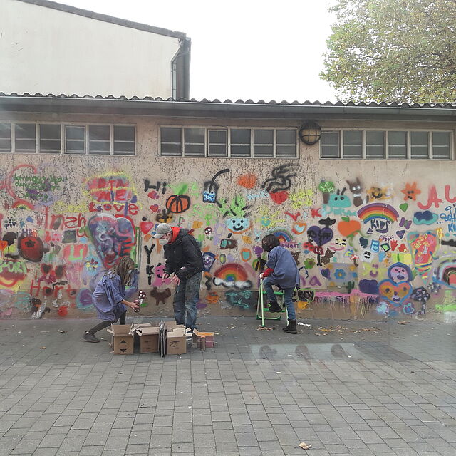 Drei Graffitikünstler vor der Turnhalle der Rosenplatzschule