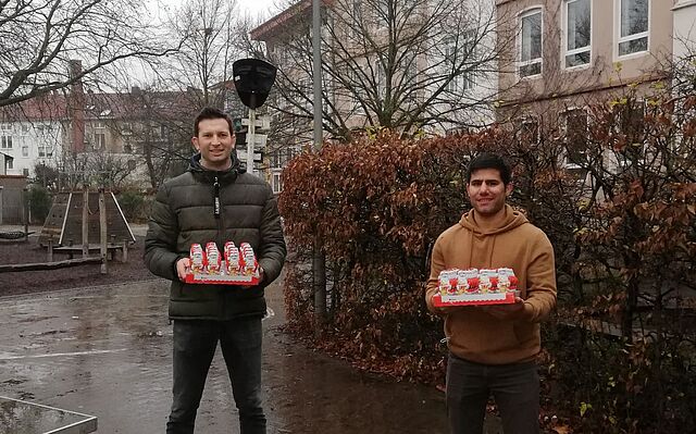 Zwei Männer halten je eine Palette Schokonikoläuse in der Hand