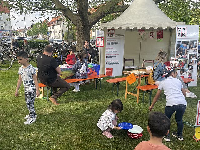 Kinder und Erwachsene sammeln sich spielend um den VPAK-Stand.