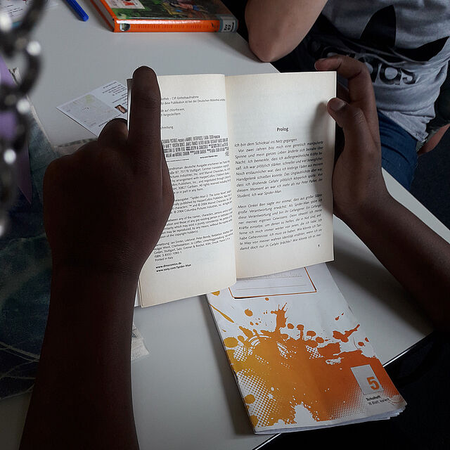 Ein aufgeschlagenes Buch wird von Kinderhänden gehalten.