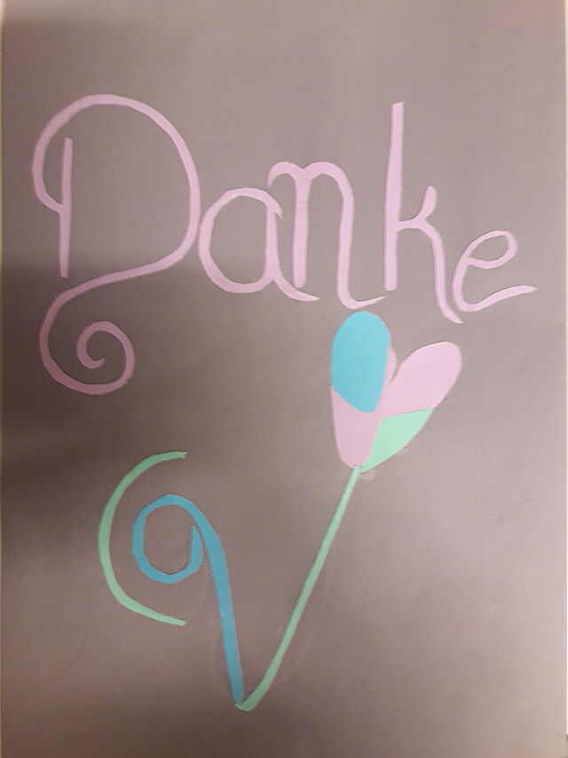 Aus Buntpapier sind eine Herzblume und DANKE auf eine Karte geklebt.