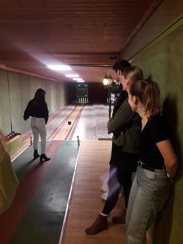 An einer Kegelbahn stehen Jugendliche.