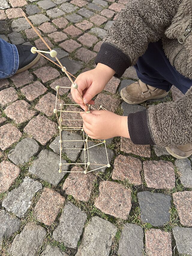 Ein Kind baut eine kleine Skulptur aus Erbsen und Zahnstochern.