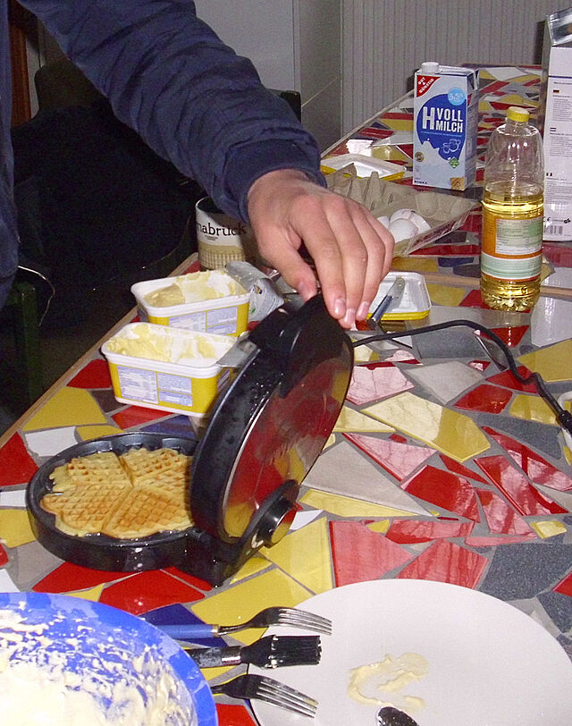 Ein Jugendlicher zeigt seine fertige Waffel im Waffeleisen.