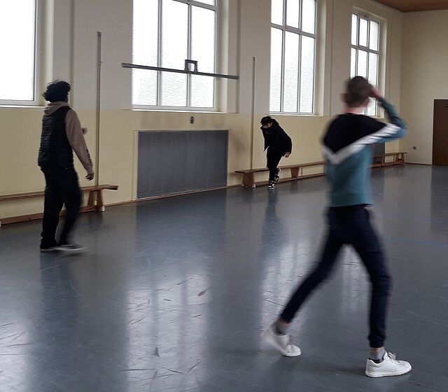 Drei Jungs spielen mit einem Ball in einer Turnhalle.
