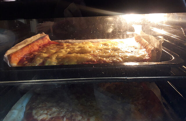 Im Backofen sieht man eine fertige Pizza.