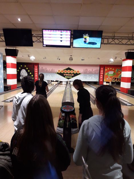 Blick auf eine Bowlingbahn mit Jugendlichen im Vordergrund.