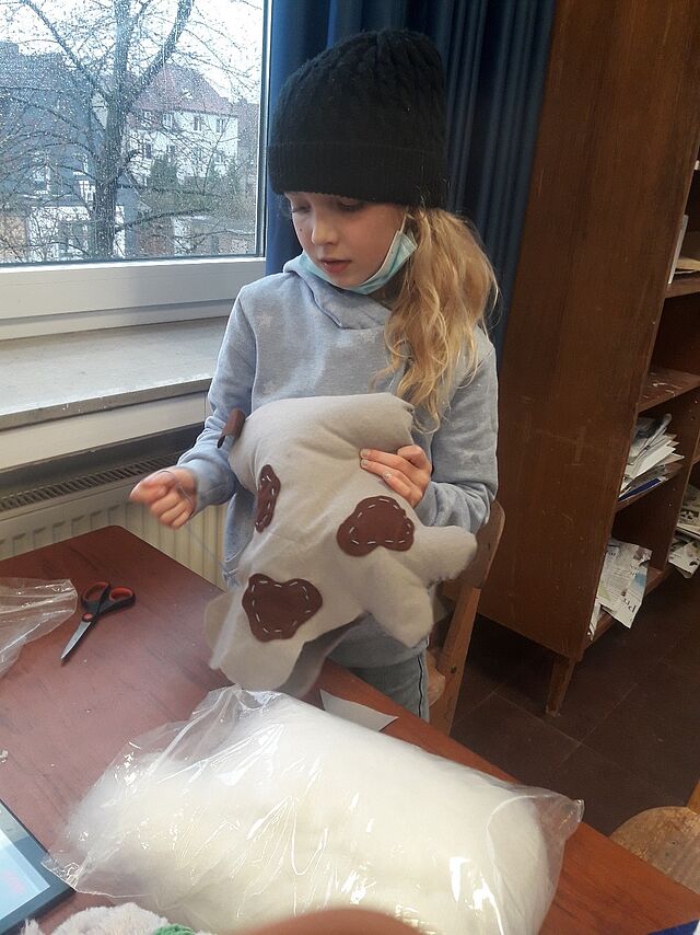 Ein Mädchen näht ein Kuscheltier