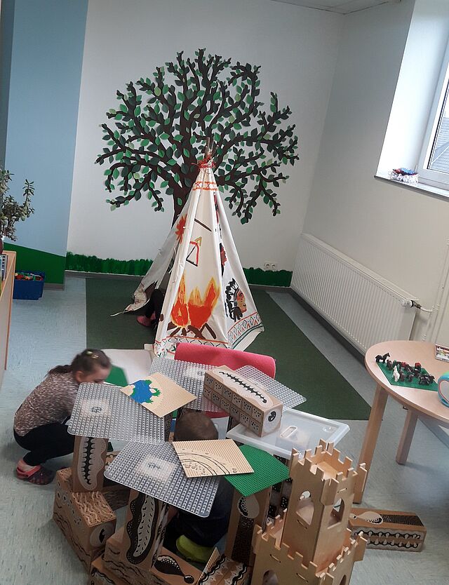 Neugestalteter Hortraum mit gemaltem Baum an der Wand, Zelt und Burg zum Spielen im Vordergrund