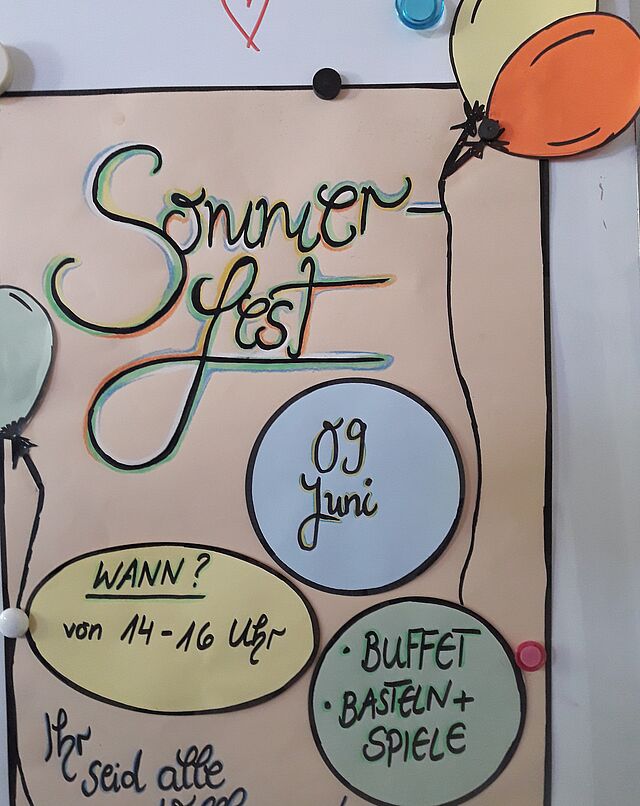 Ein selbstgebasteltes Plakat läd zum Sommerfest ein.