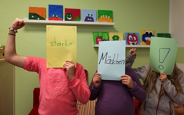 Drei Mädchen halten Bilder hoch, mit der Aufschrift: STARKE MÄDCHEN!
