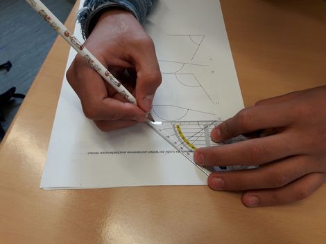 Ein Schüler zeichnet ein Dreieck im Geometrieunterricht. 