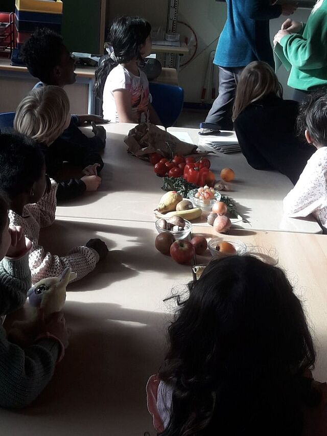 Die Kinder sitzen am Tisch, wo Obst und Gemüse liegen