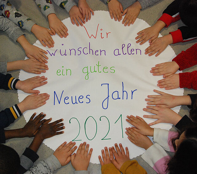 Kinderhände auf einem Plakat mit Neujahrwünschen