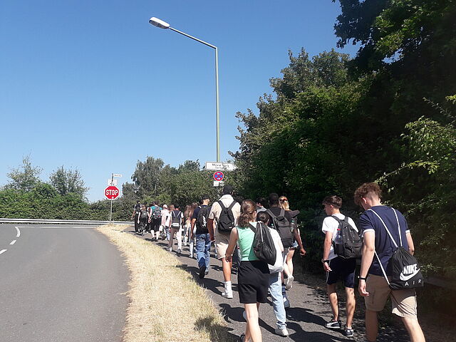 Eine große Menschengruppe geht eine Straße entlang.